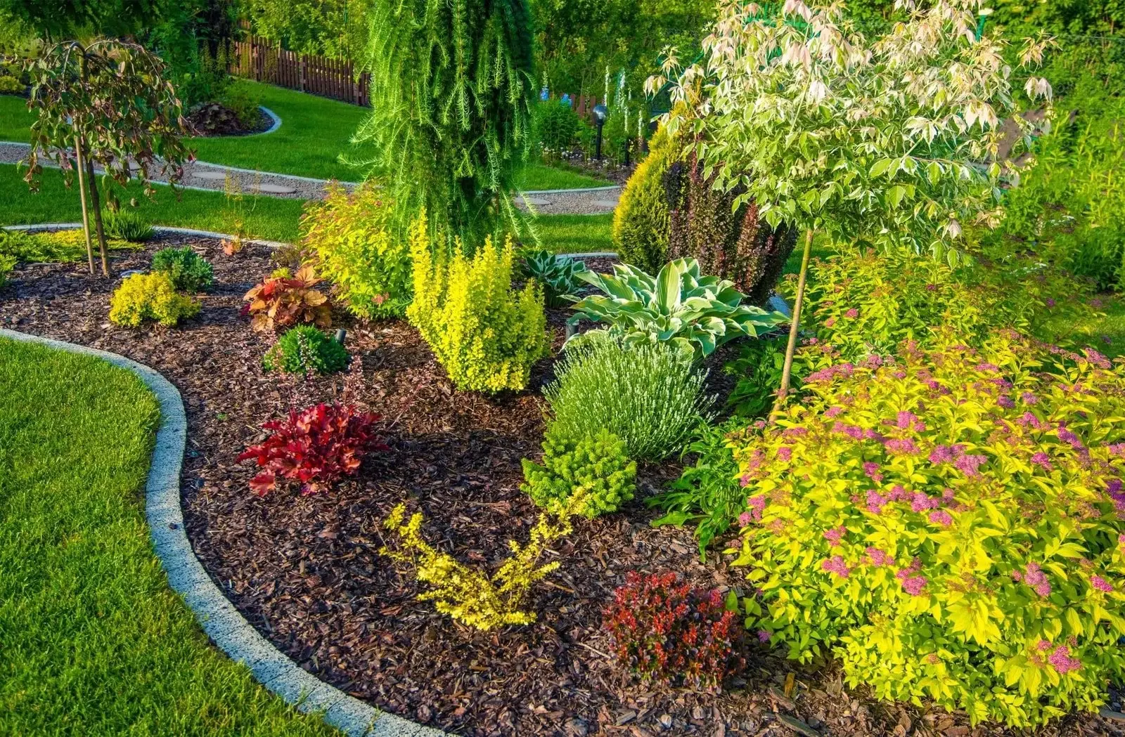 Highland estate landscaping with structured shrubbery and dark mulch beds